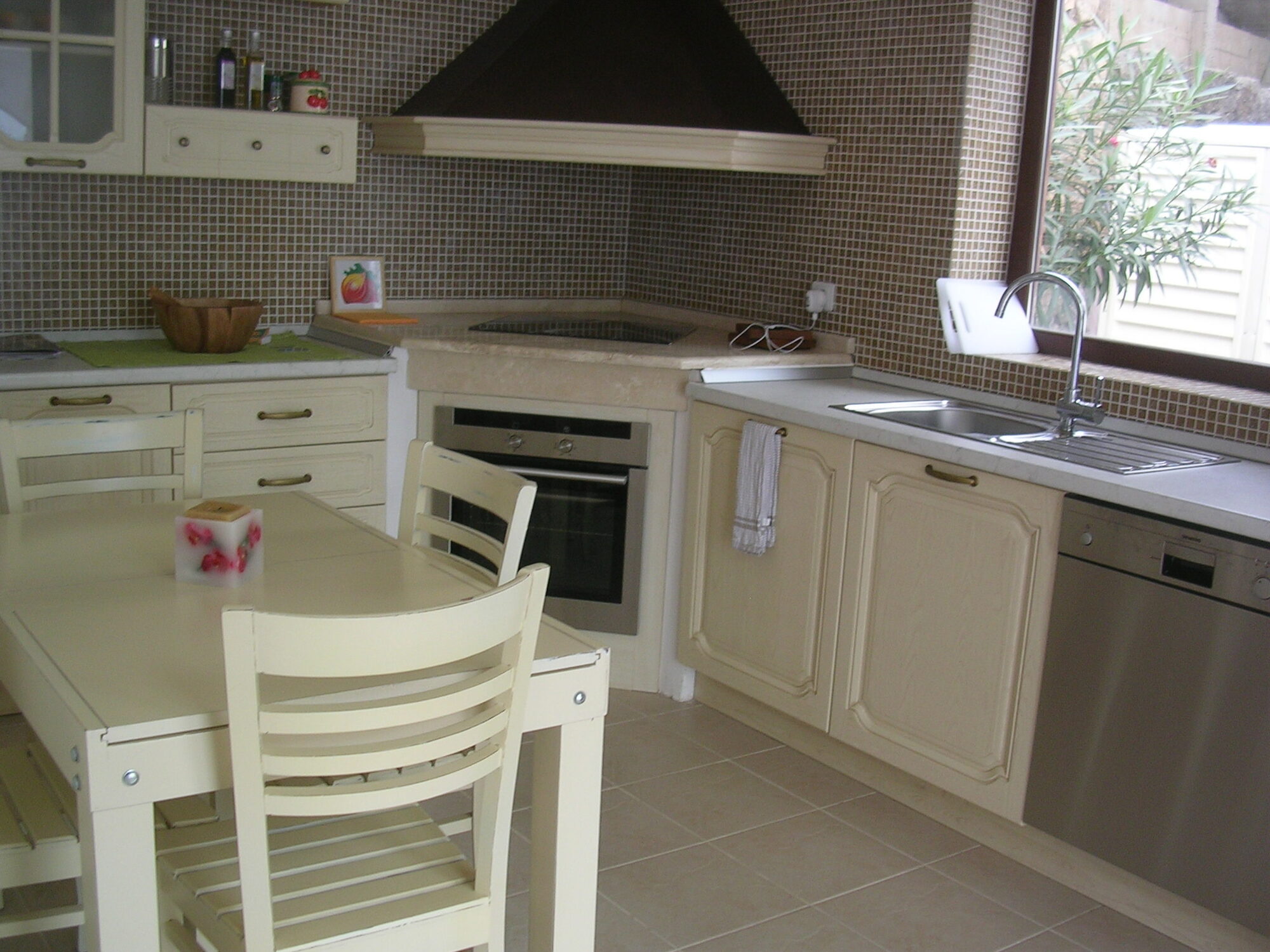 Kitchen with cream cabinets, mosaic splashback and stainless steel appliances