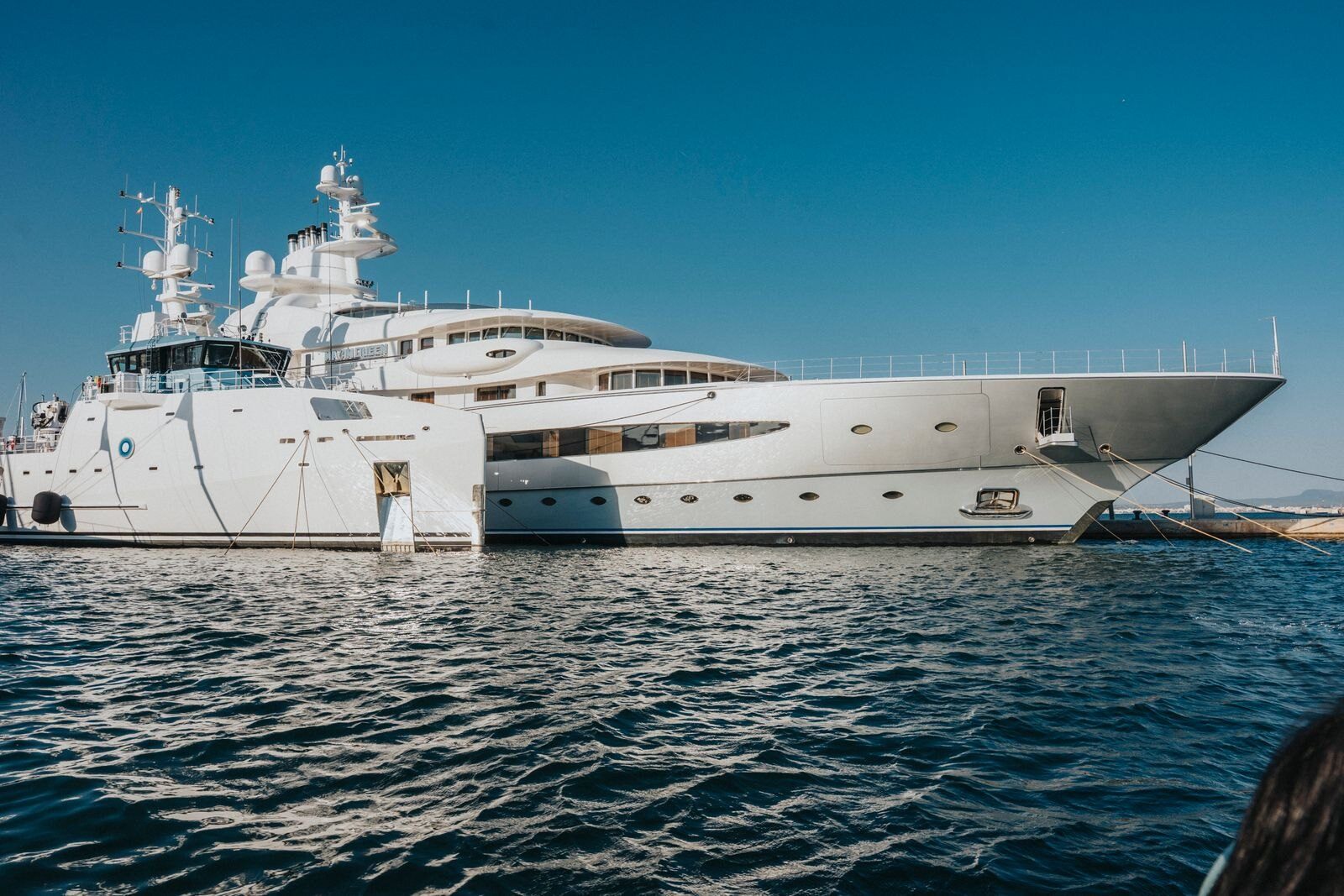 A large modern superyacht moored in a marina